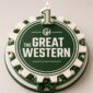 A dark green and white gear-shaped cake for 'The Great Western' with a lit number 1 candle on top. The cake features white text, a 'GW' logo, and decorative green and white frosting details.